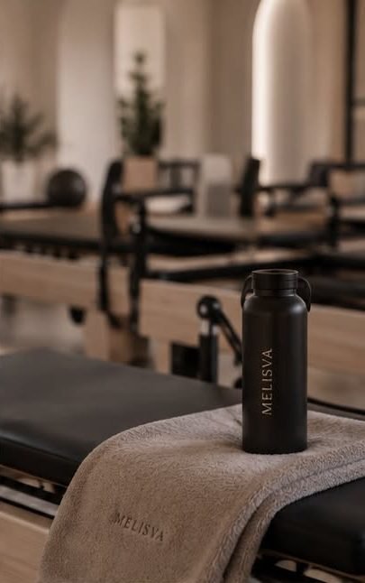 Melisva water bottle and towel resting on a Pilates reformer
